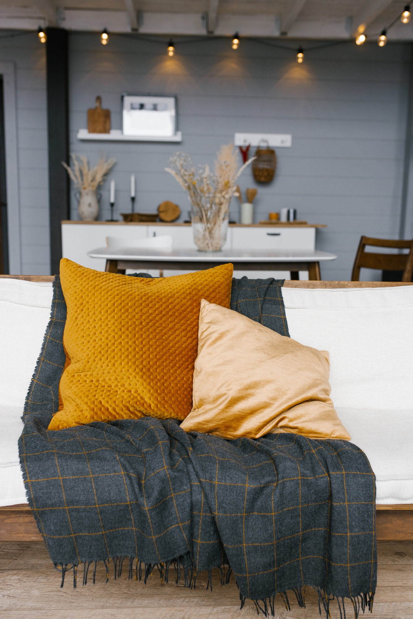 Mustard pillows and a dark plaid plaid on the white sofa in the modern living room.